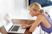 10386686-happy-young-woman-sitting-at-home-working-on-laptop-computer